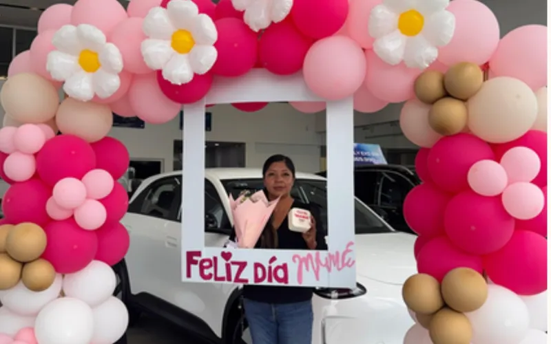 Arco de globos y marco fotográfico junto a un vehículo en el showroom de Geely Metepec