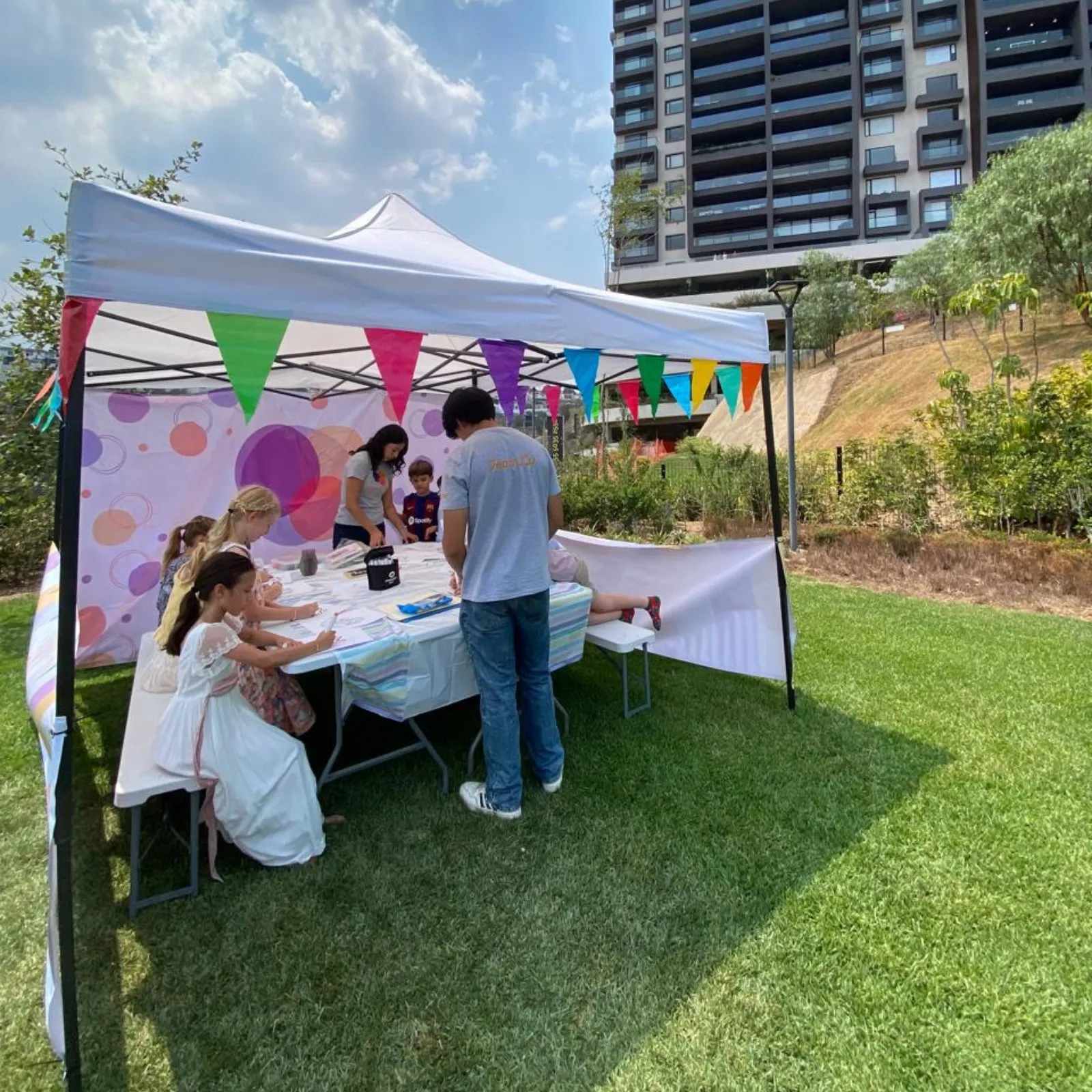 Rincón de manualidades y experimentos montado en carpa, con niños haciendo actividades en la mesa